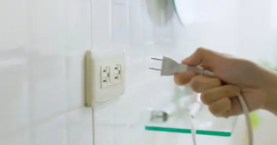 hand holding a plug near an outlet